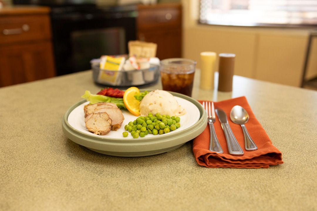 A plate of food with meat , peas , and rice on a table.