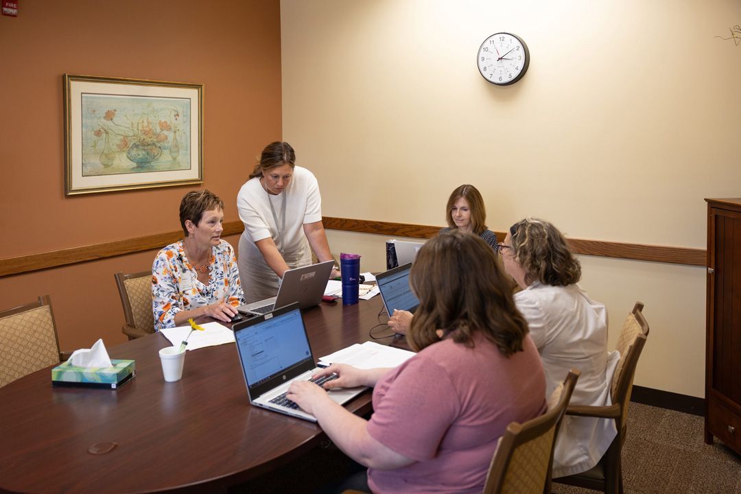 A group of women are sitting around a table with laptops.