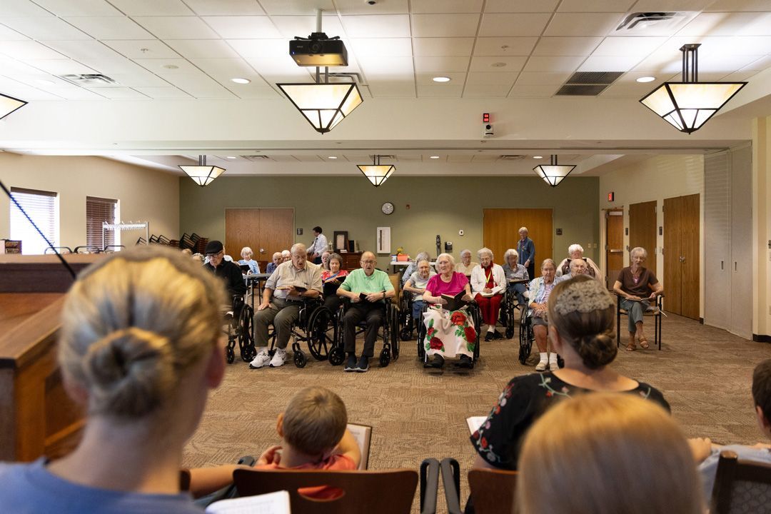A group of people in wheelchairs are sitting in a large room.