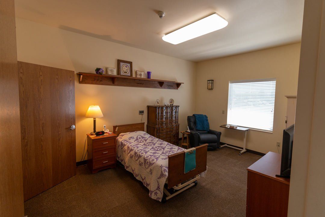 A bedroom with a bed , chair , nightstand and television.