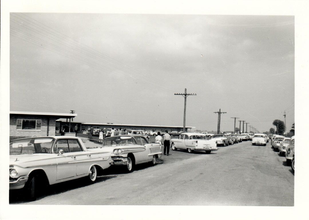 A black and white photo of cars parked on the side of the road