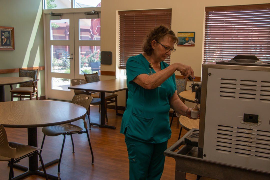 A woman in scrubs is working on a machine in a dining room.