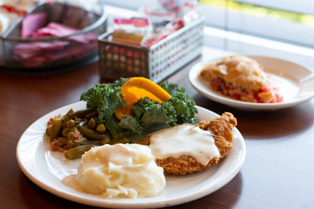 A plate of food with mashed potatoes green beans and chicken on a table.