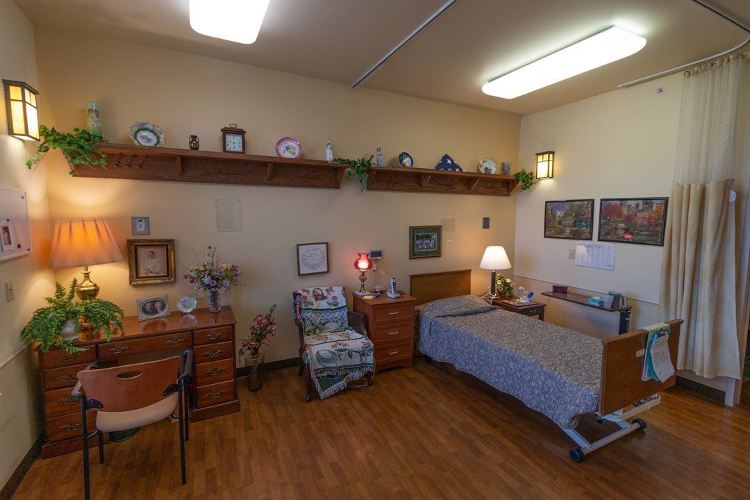 A bedroom with a bed , desk , chair and lamp.