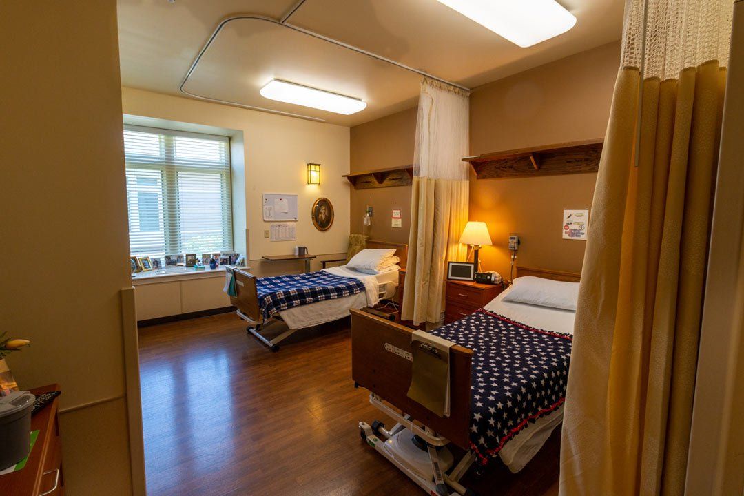 A hospital room with two beds and a window.