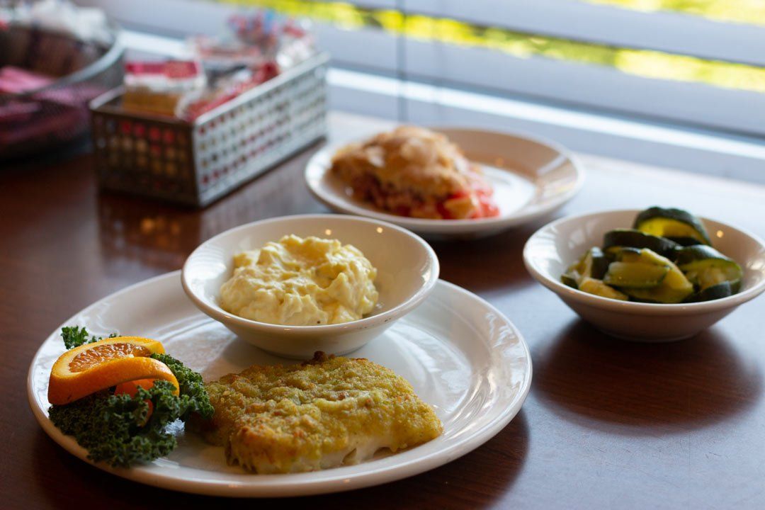 A table topped with plates of food including mashed potatoes and pickles.