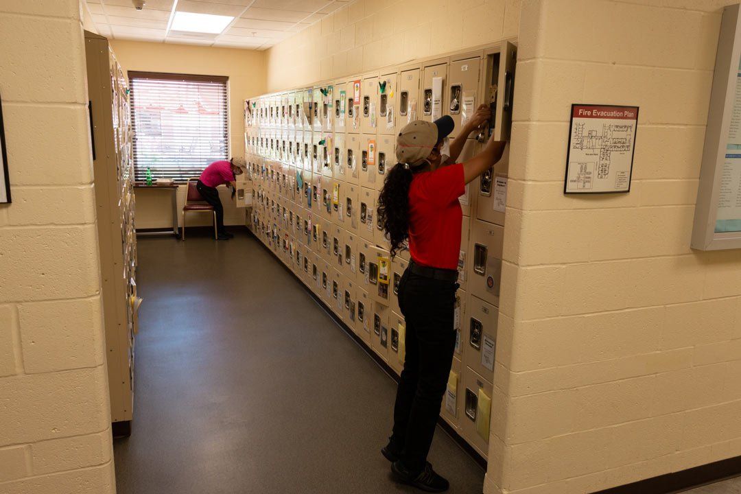 A man in a red shirt is cleaning lockers in a hallway.