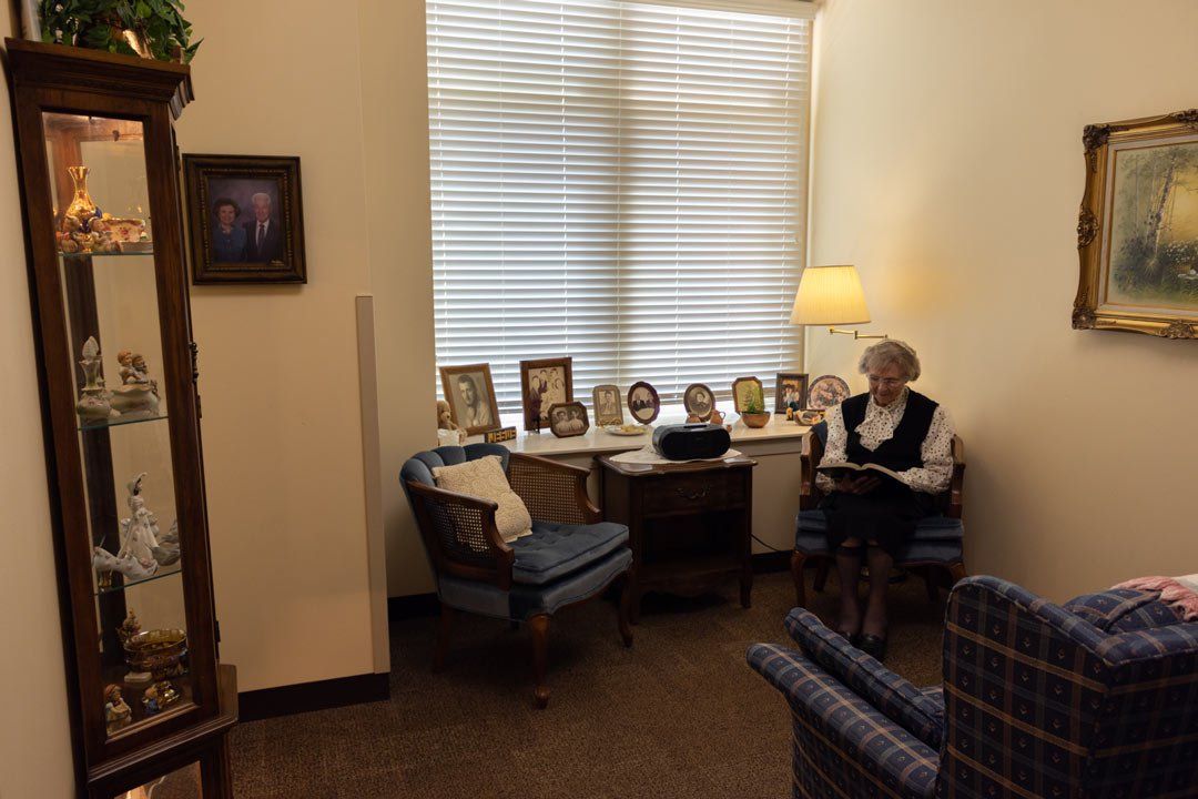 A woman is sitting in a chair reading a book in a living room.