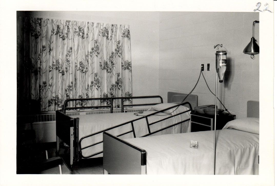 A black and white photo of a hospital room with two beds