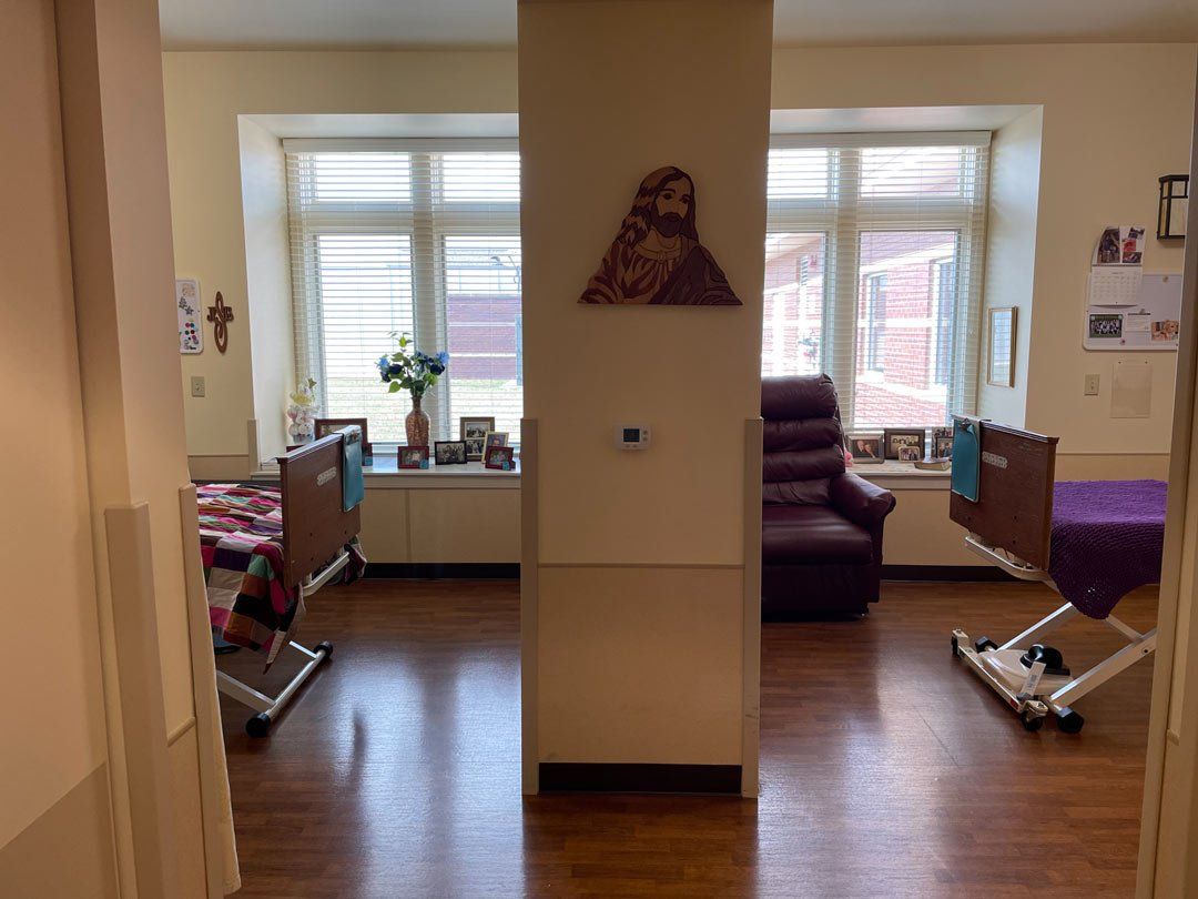 A hospital room with two beds , a chair and a window.