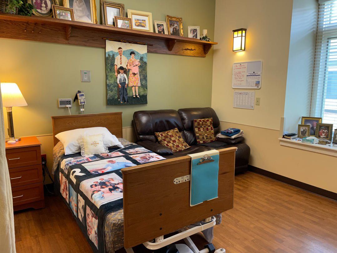 A bedroom with a bed , couch , nightstand and pictures on the wall.