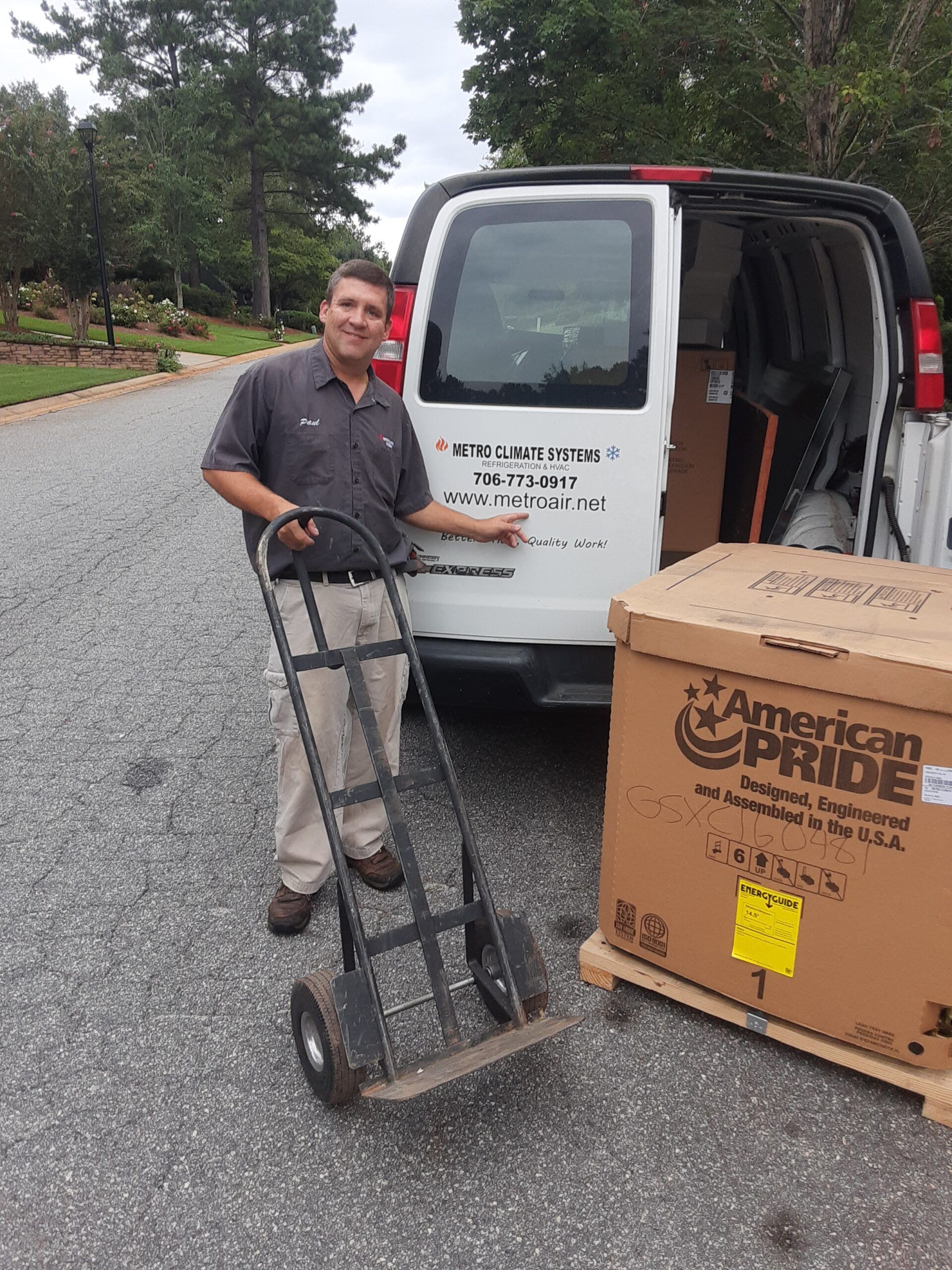 A man is pushing a hand truck in front of a van.