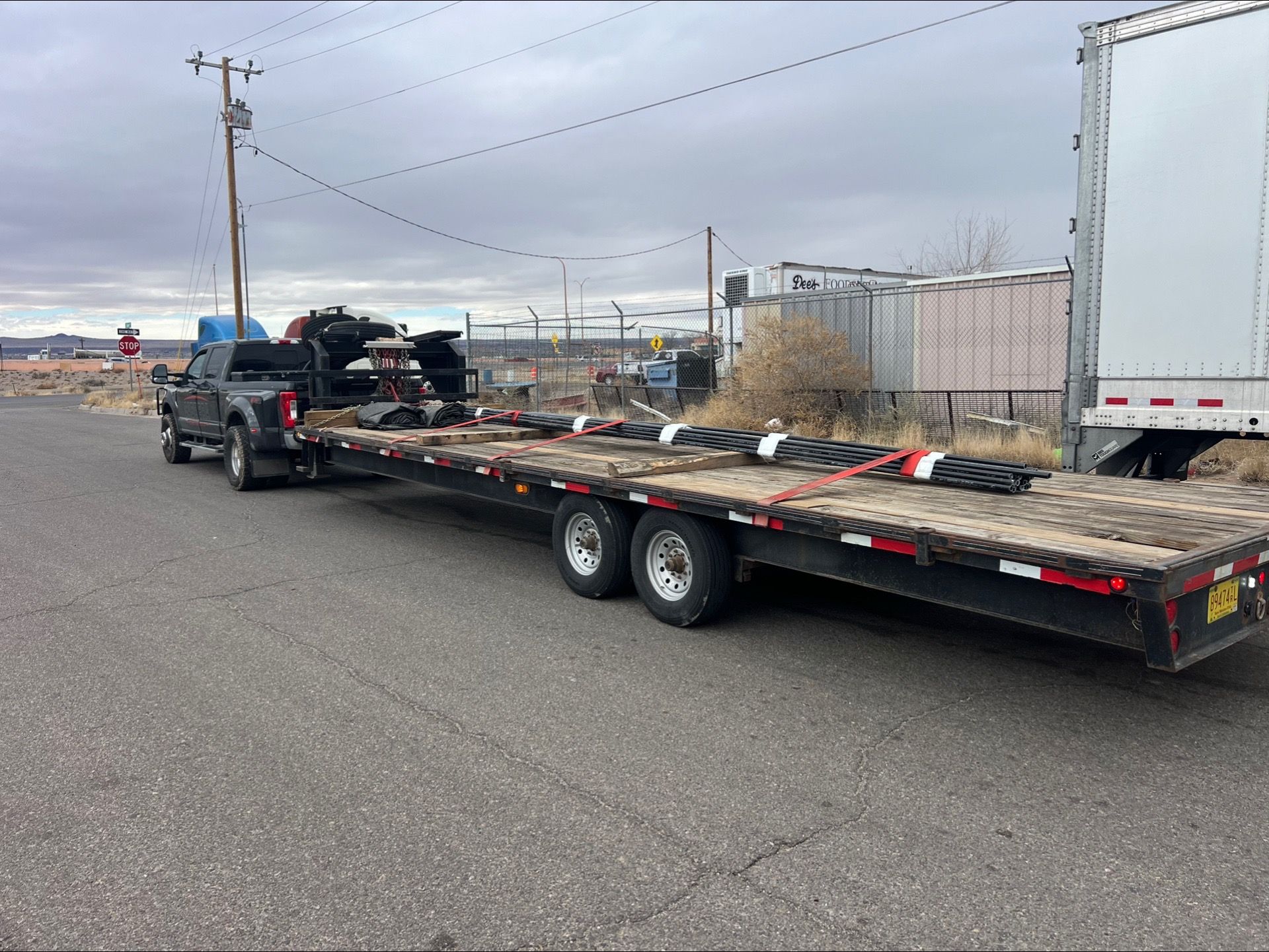 Flatbed trailer loaded with equipment parked beside a truck in an industrial lot
