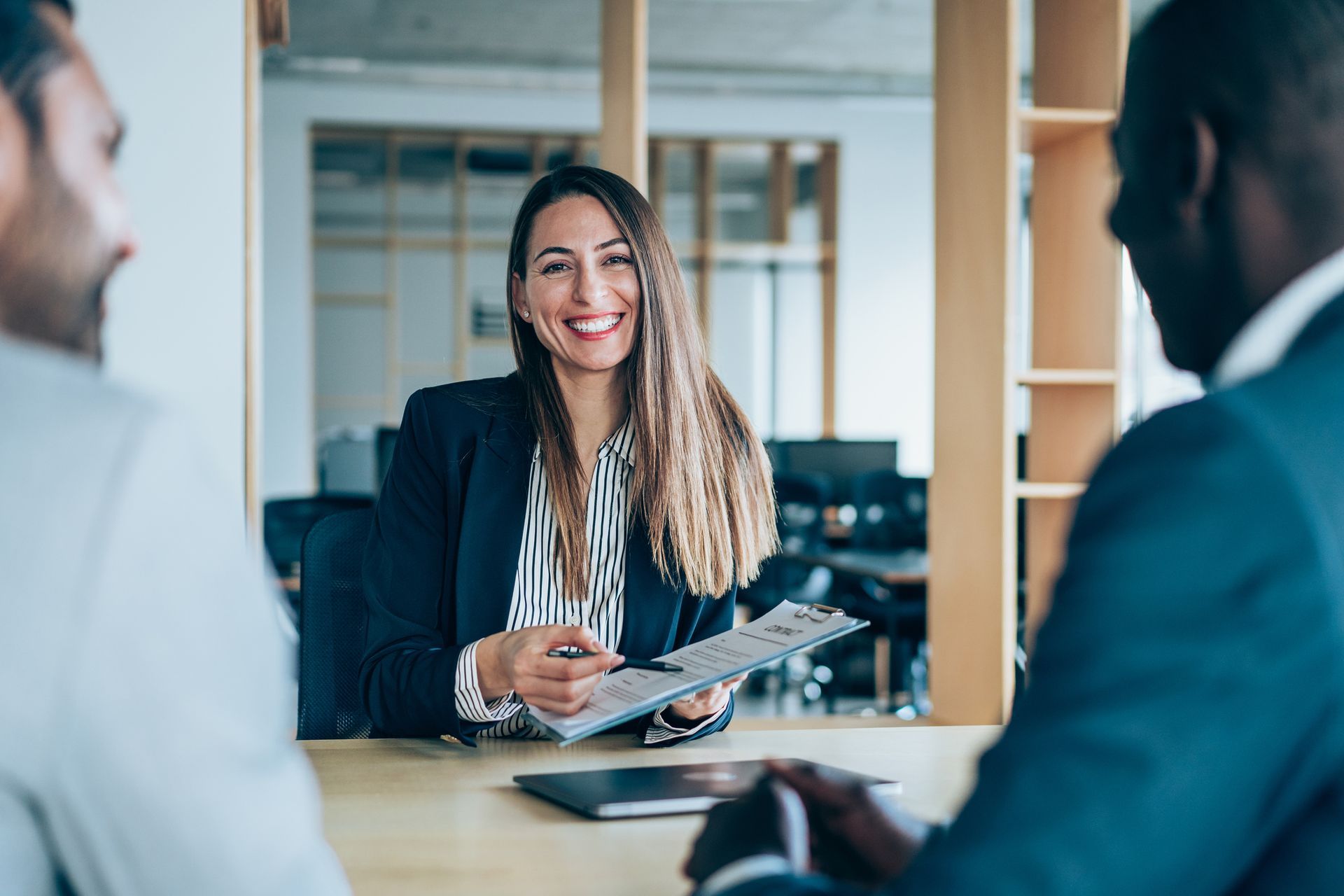 A man and a woman are sitting at a table talking to a woman.