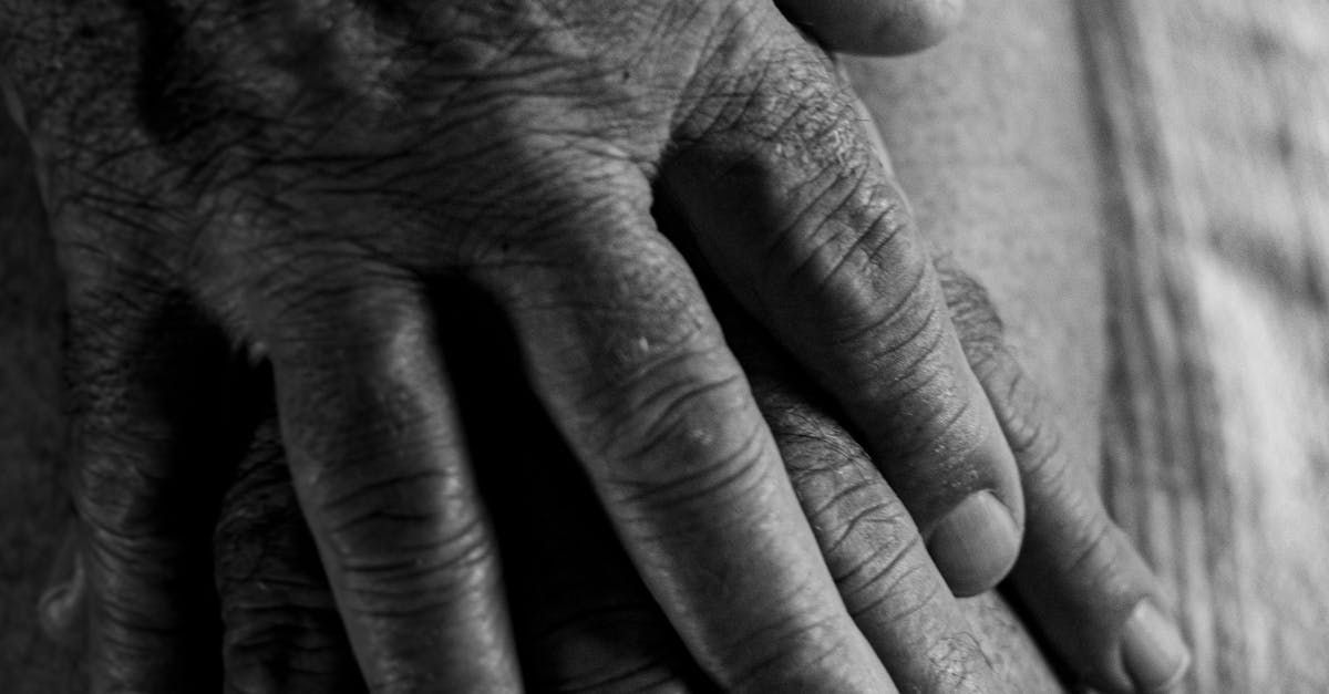Close-up of weathered hands resting on a light-colored surface, showing wrinkles and skin texture.