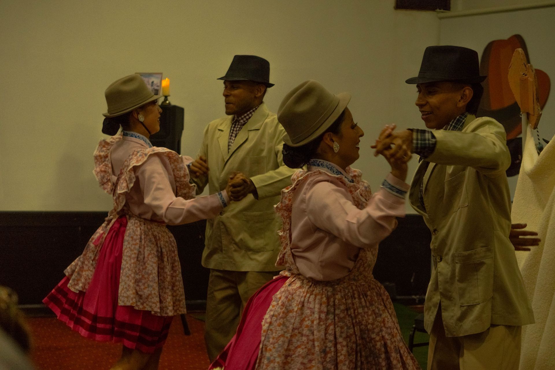 Four people in traditional Peruvian outfits dancing indoors.