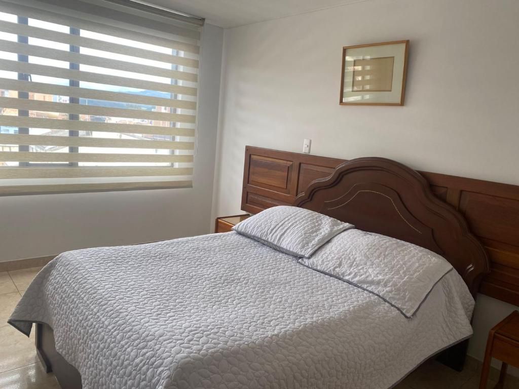 Bedroom with a bed, window with blinds, and a framed artwork.
