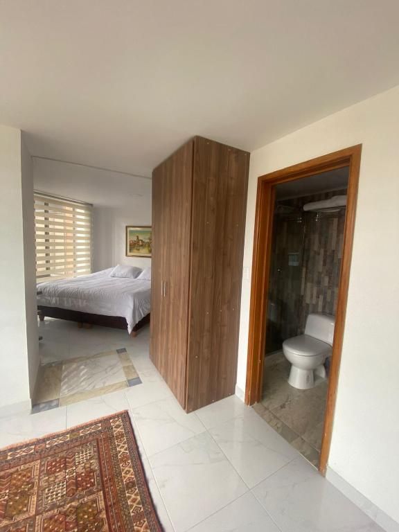 Bedroom view with bed, closet, and bathroom visible. Room has tile and rug.