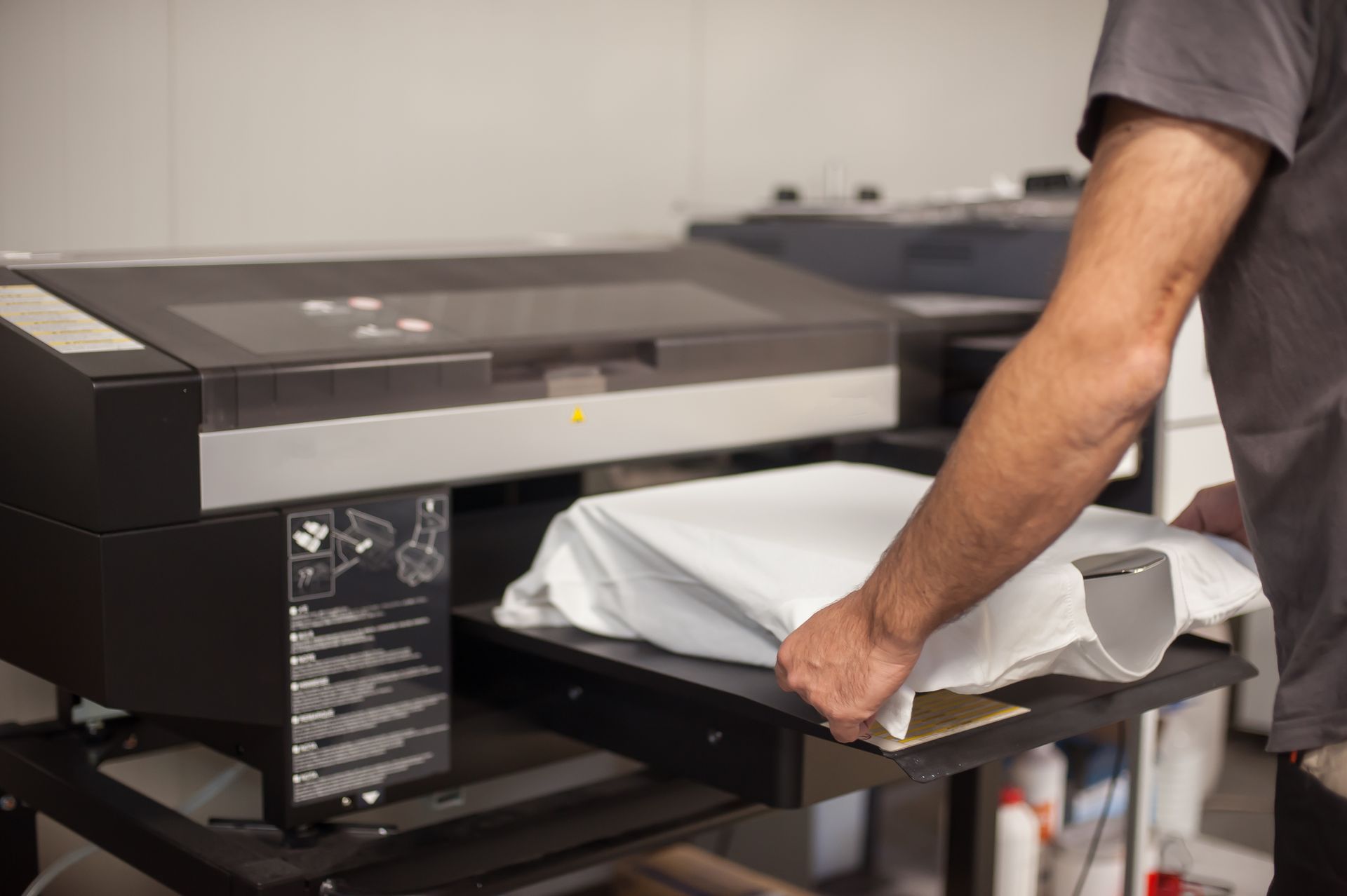 Person placing a white t-shirt onto a printing machine