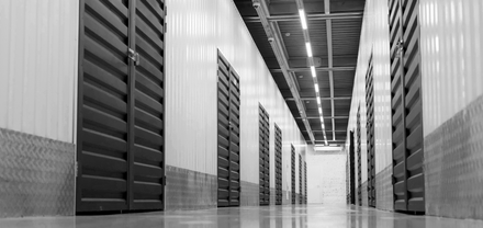 A black and white photo of a long hallway filled with lots of lockers.