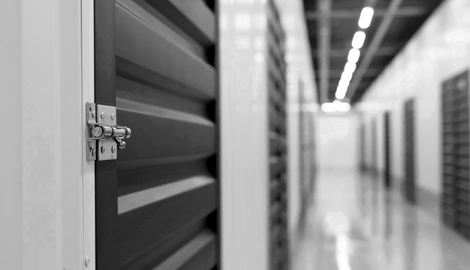 A black and white photo of a storage room with a door open.