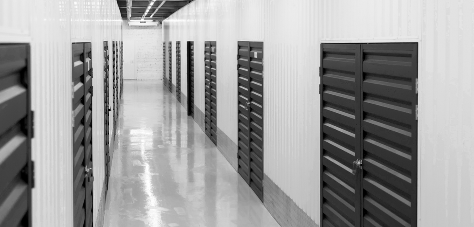 A black and white photo of a hallway filled with rows of lockers.