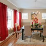 A dining room with a table and chairs and red curtains.