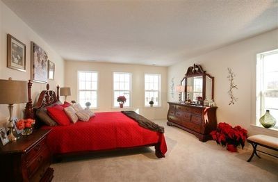 A bedroom with a bed , dresser , mirror and lamps.