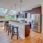 A kitchen with stools , a refrigerator , and a large island.