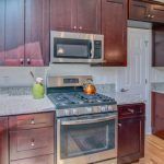 A kitchen with a stove , microwave , and cabinets.
