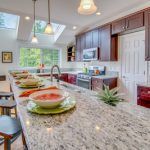 A kitchen with a long granite counter top and plates on it.