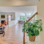 A potted plant is sitting on a table in a living room next to a staircase.