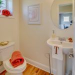 A bathroom with a toilet , sink and mirror.