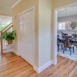 A hallway with hardwood floors leading to a dining room and stairs.