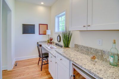A kitchen with granite counter tops and white cabinets.