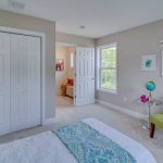 A bedroom with a bed , closet , chair and window.