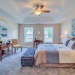 There is a ceiling fan in the bedroom with a large bed.