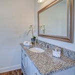 A bathroom with a sink , mirror and granite counter top.