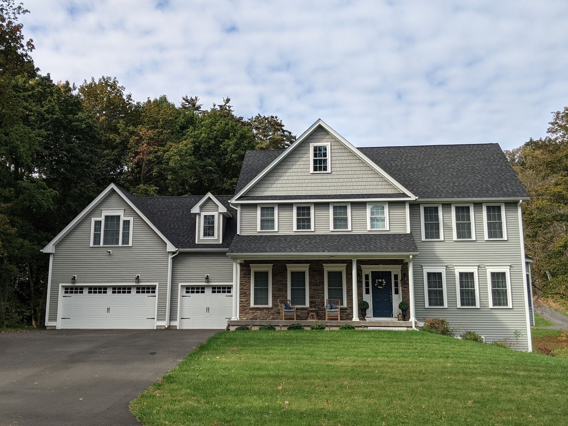 A large house with a gray siding and a black roof