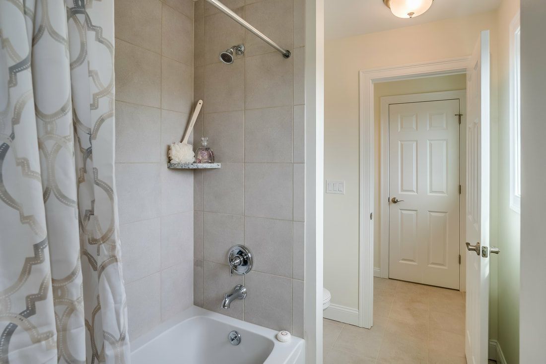 A bathroom with a tub , shower , and door.
