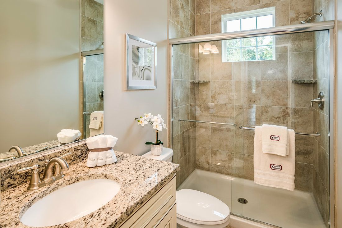A bathroom with a sink , toilet , shower and mirror.