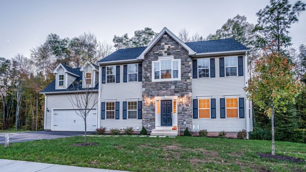 A large white house with a blue roof is surrounded by trees.