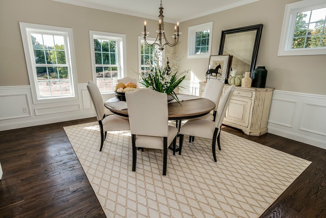 A dining room with a table and chairs and a rug.