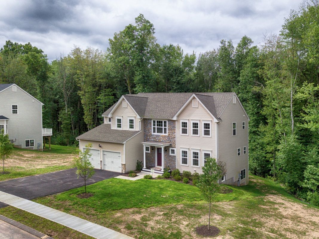 An aerial view of a house in a residential area surrounded by trees.