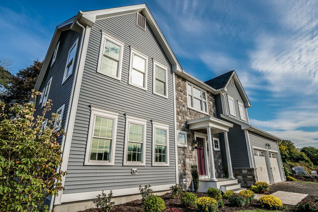 A large gray house with a lot of windows and a red door.