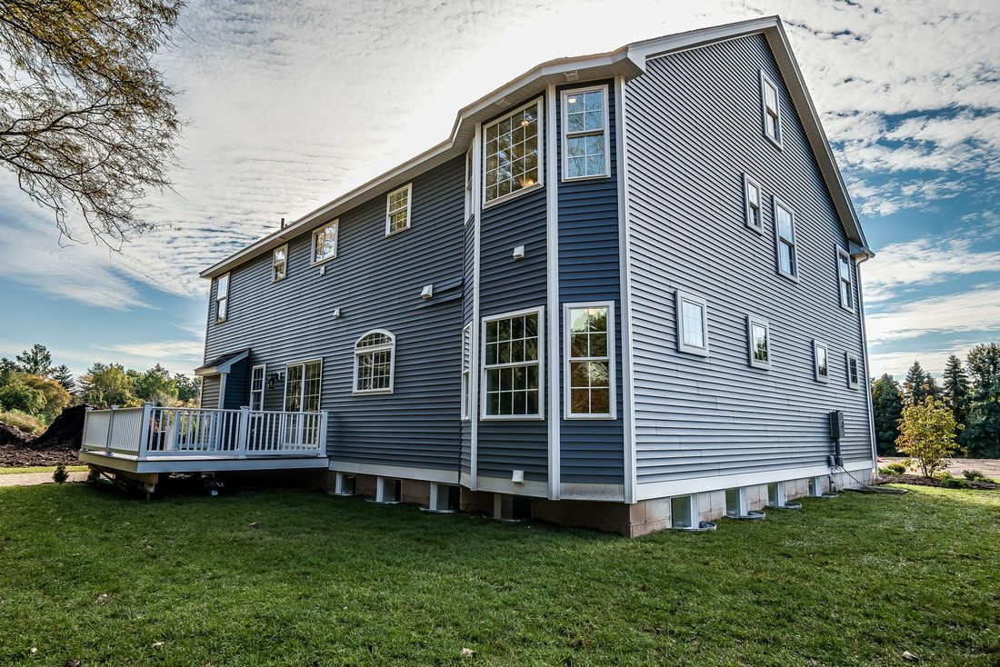 A large house with a lot of windows is sitting on top of a lush green field.