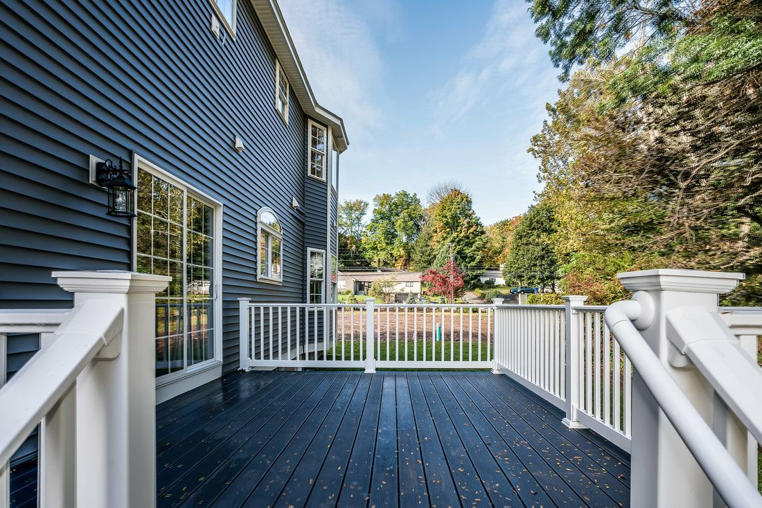 A large deck with a white railing in front of a house.
