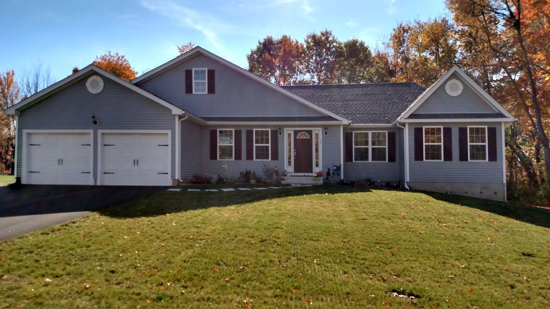 A large house with two garages is sitting on top of a lush green lawn.