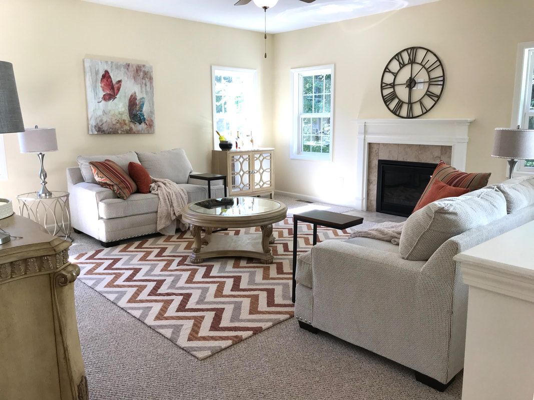A living room filled with furniture and a fireplace with a clock on the wall.