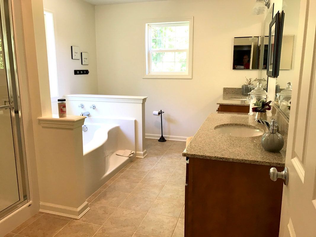 A bathroom with two sinks , a tub and a window.